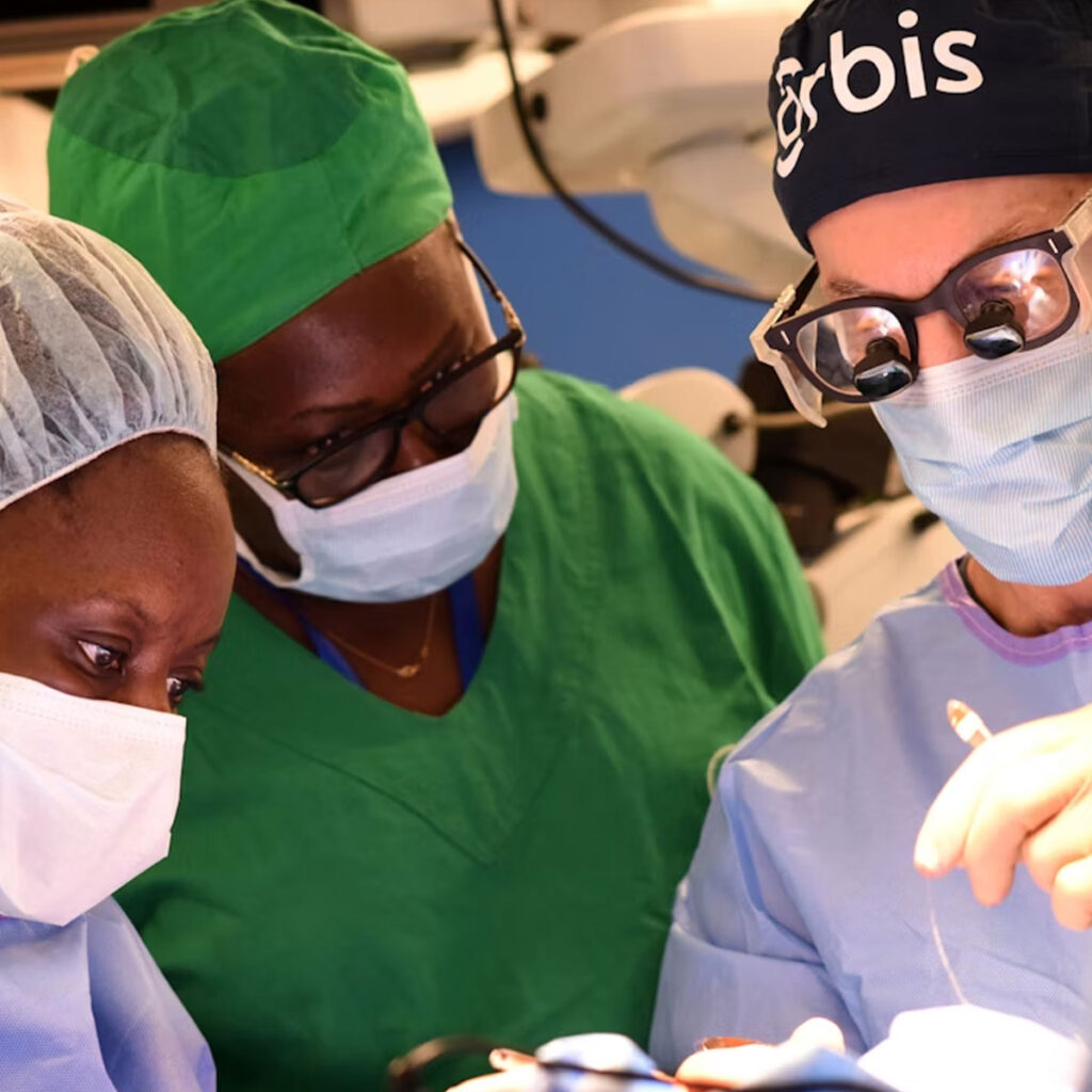 Doctor overseeing eye surgery while students operate and look on