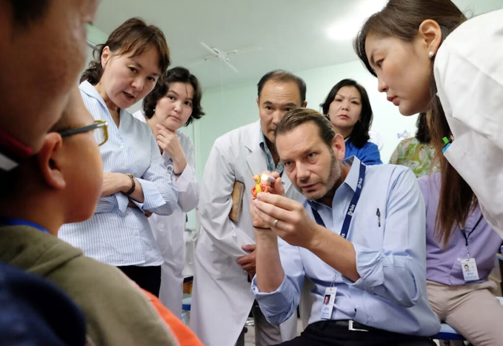 Volunteer, Dr. Daniel Neely, shows students how to screen a young patient while using a Winnie the Pooh toy.